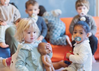 Deux petites filles jouant avec un groupe d'enfant au sein d'une crèche Babilou.