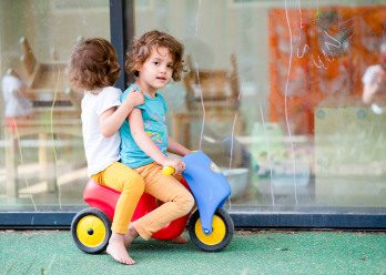 Deux enfants jouant sur un véhicule en plastique au sein d'une crèche Babilou