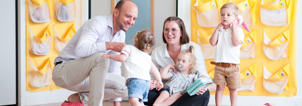 Un parent, une professionnelle et des enfants discutent en crèche Babilou