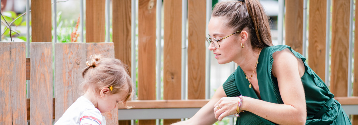 Une professionnelle de crèche avec un enfant dans un jardin