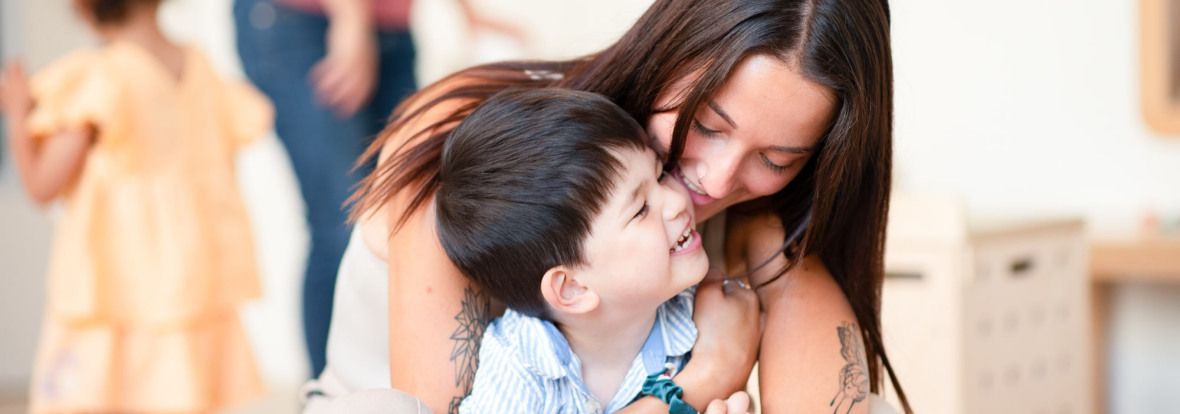 Une professionnelle de crèche fait un câlin à un enfant