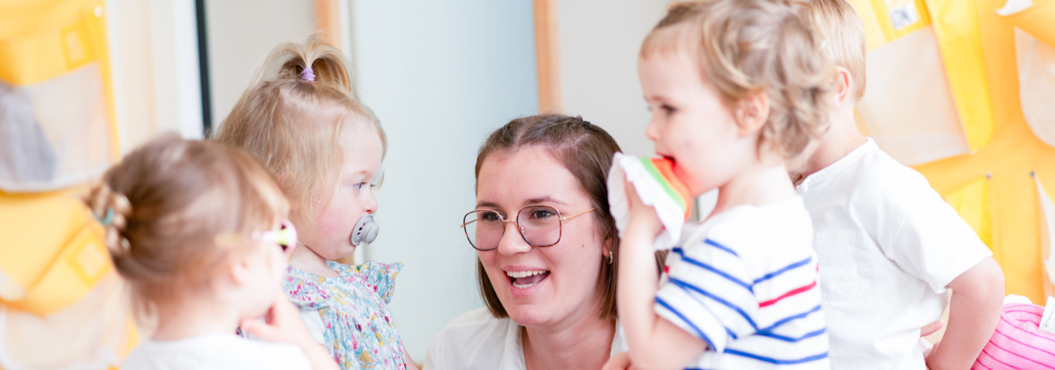 Professionnelle en crèche entourée d'enfant rigolant