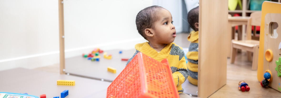 Un enfant assit entouré de jouets