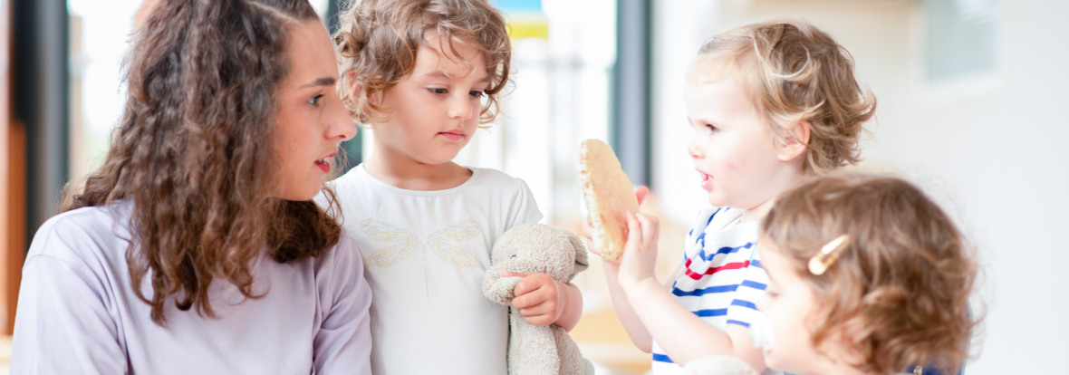 Professionnelle en crèche discutant avec un groupe d'enfants