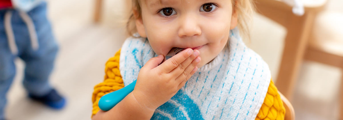 Petite fille s'essuyant la bouche durant l'heure du repas au sein d'une crèche Babilou