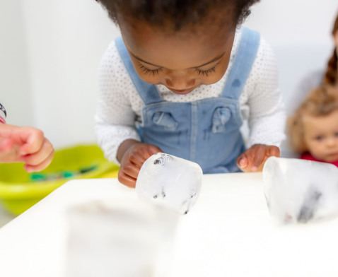 Enfant en crèche Babilou en activité sensorielle avec des glaçons