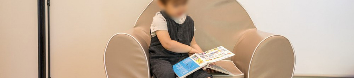 Un enfant lit un livre sur un siège.