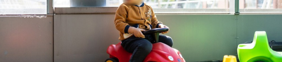 Un enfant fait du trotteur dans l'espace extérieur de la crèche. 