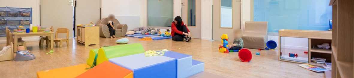 Les enfants jouent dans la salle de jeux de la crèche sous le regard attentif d'une professionnelle de la petite enfance.