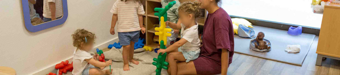 Une professionnelle en crèche jouant avec un groupe d'enfant 