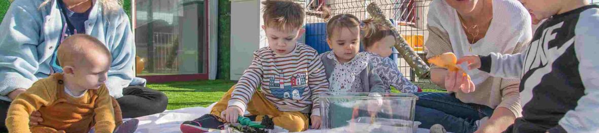 Un groupe d'enfant en crèche et deux pro jouant dans le jardin