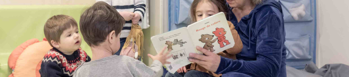 Une pro qui lit un livre à un groupe d'enfant en crèche 