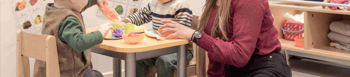 Une professionnelle en crèche assise entouré de deux d'enfant 