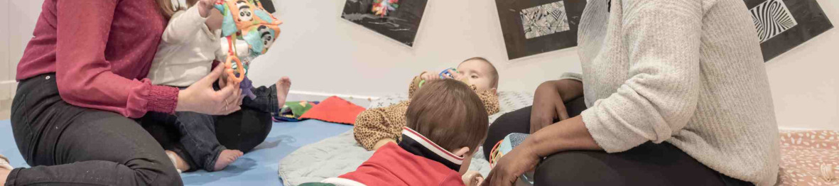 Deux pro en crèche avec deux enfants sur un tapis d'éveil 