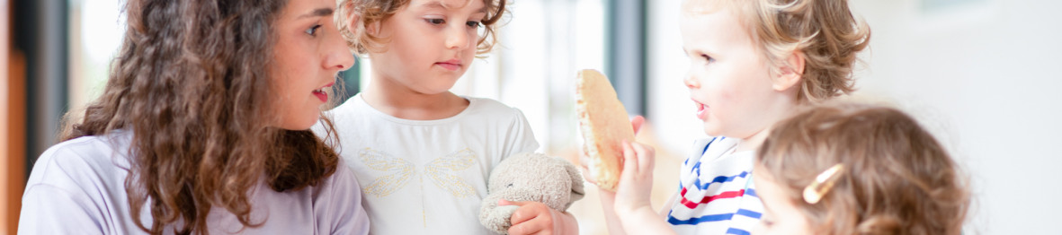 Professionnelle en crèche discutant avec un groupe d'enfants
