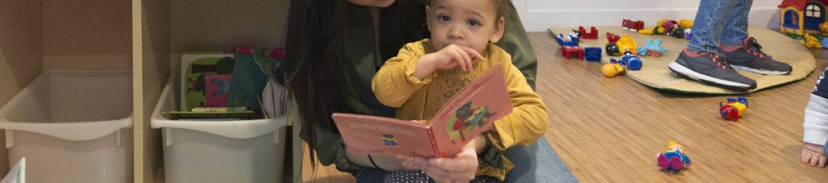 Une professionnelle en crèche Babilou qui lit un livre à une enfant