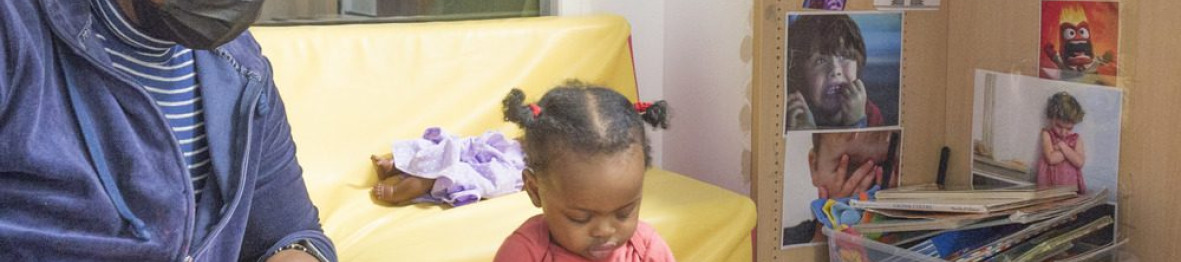 Une professionnelle en crèche qui lit un livre à une enfant