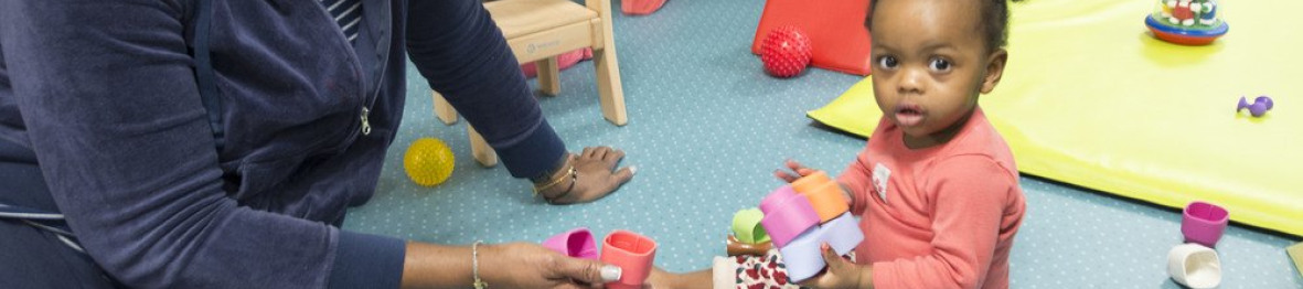 Une professionnelle en crèche qui joue avec une enfant