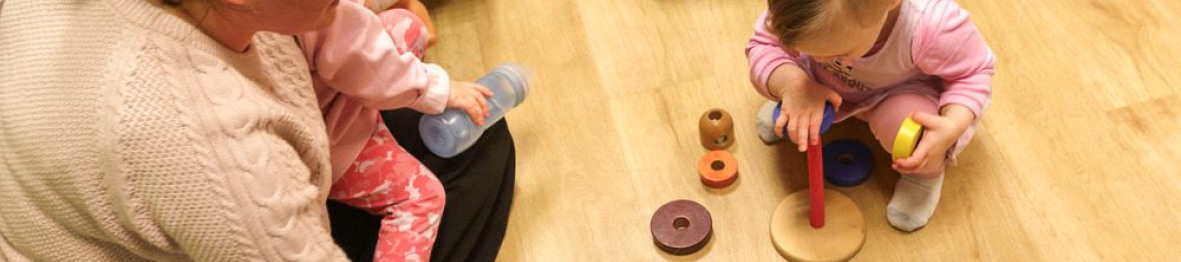 Une professionnelle en crèche assise entouré d'un groupe d'enfants