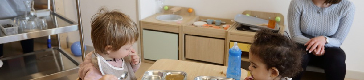 Une pro crèche en crèche et deux enfants qui mangent 