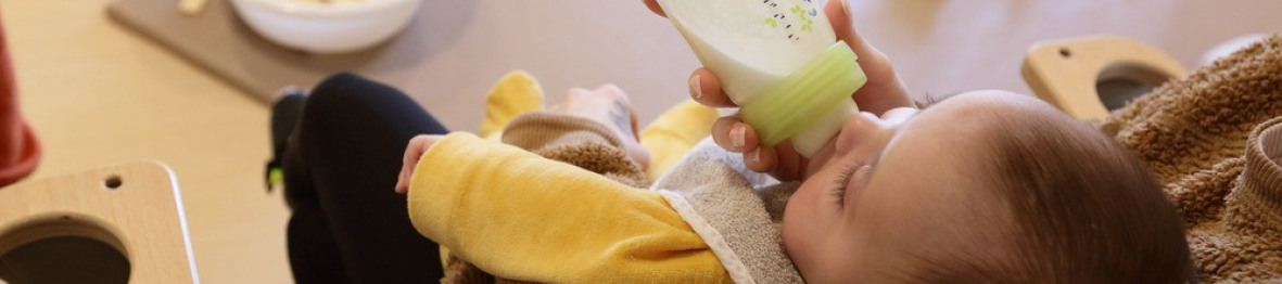 Une pro en crèche qui donne le biberon à un bébé 