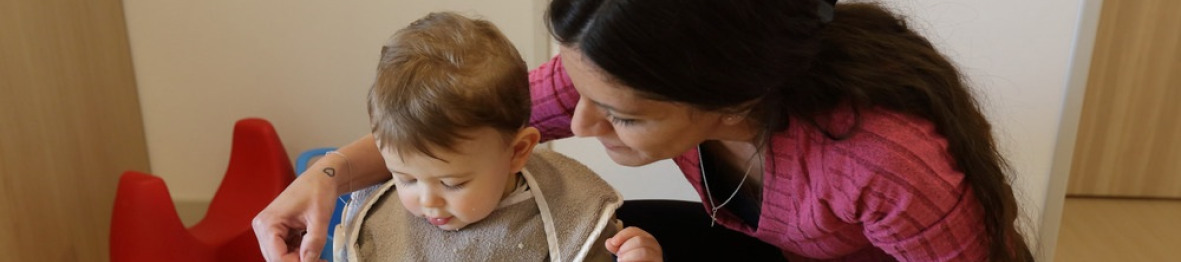 Une pro en crèche qui aide un enfant à manger 