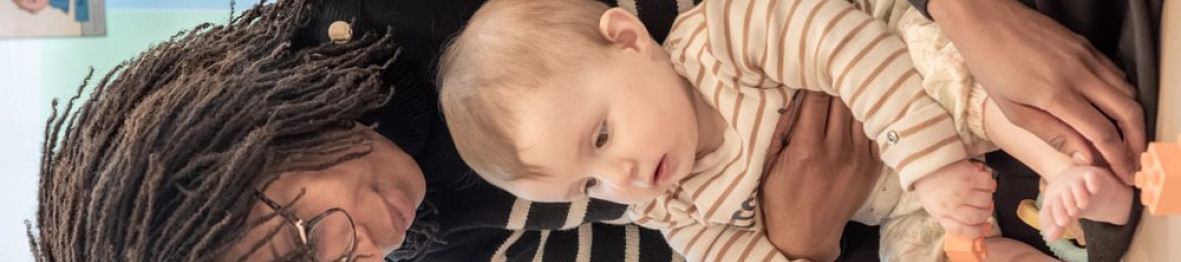 Une professionnelle en crèche assise avec un bébé