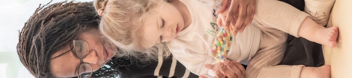 Une professionnelle en crèche assise avec un enfant