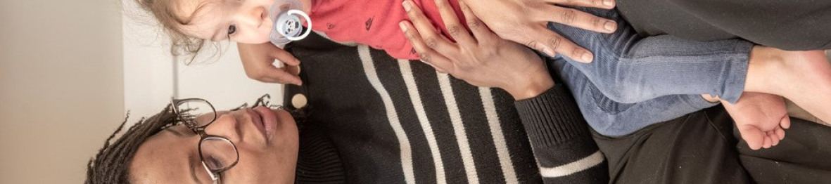 Une professionnelle en crèche assise avec un enfant