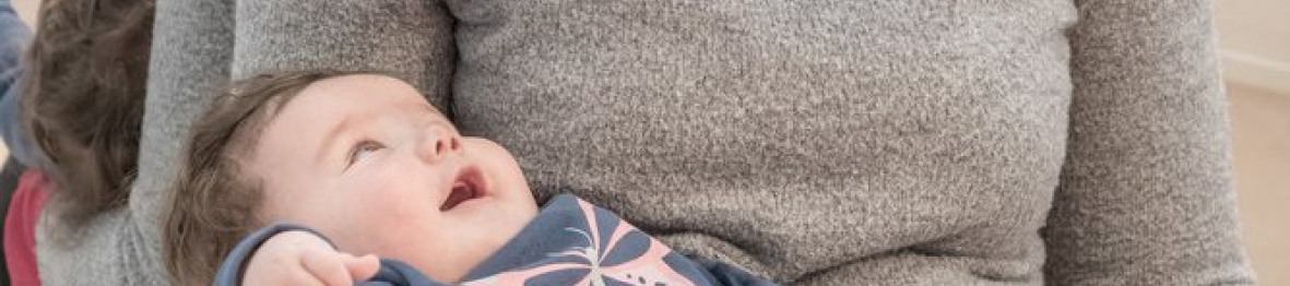 Une professionnelle en crèche assise avec un bébé