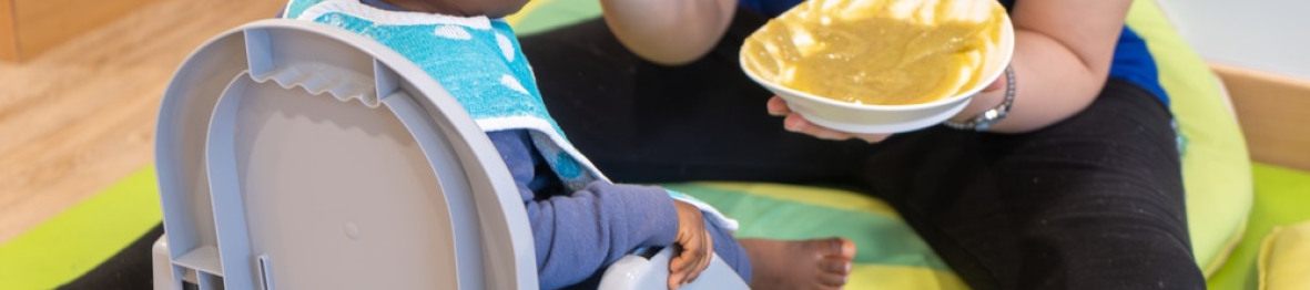 Une pro en crèche qui donne à manger à un enfant
