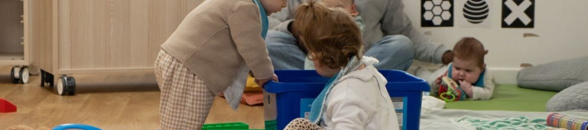 Une professionnelle en crèche assise entouré de trois d'enfants 