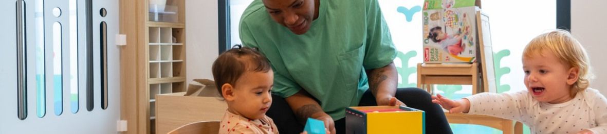 Une pro en crèche en interaction avec deux enfants 