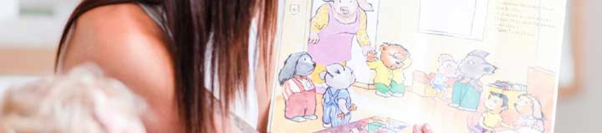 Professionnelle lisant un livre à des enfant au sein d'une crèche