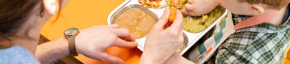 Une pro en crèche qui donne à manger à un enfant