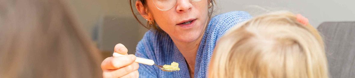 Une pro en crèche qui donne à manger à un enfant