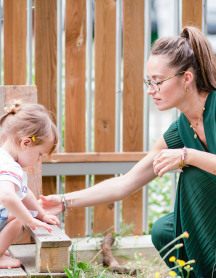 Une professionnelle de crèche avec un enfant dans un jardin
