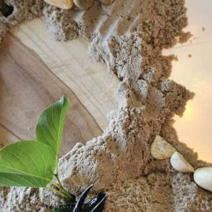 Des jouets en forme de dinosaures mis en scène avec du sable et des feuilles