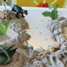 Une mise en scène avec des jouets dinosaures dans un décor avec des pierres et du sable 