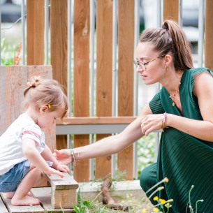 Une professionnelle de crèche avec un enfant dans un jardin