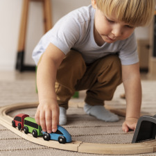 Un petit garçon jouant avec un circuit de train en bois