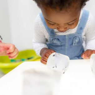 Enfant en crèche Babilou en activité sensorielle avec des glaçons