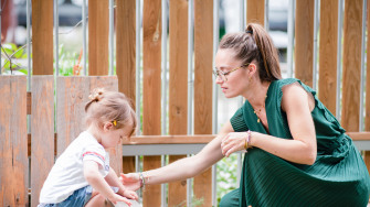 Une professionnelle de crèche avec un enfant dans un jardin