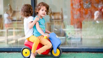 Deux enfants jouant sur un véhicule en plastique au sein d'une crèche Babilou